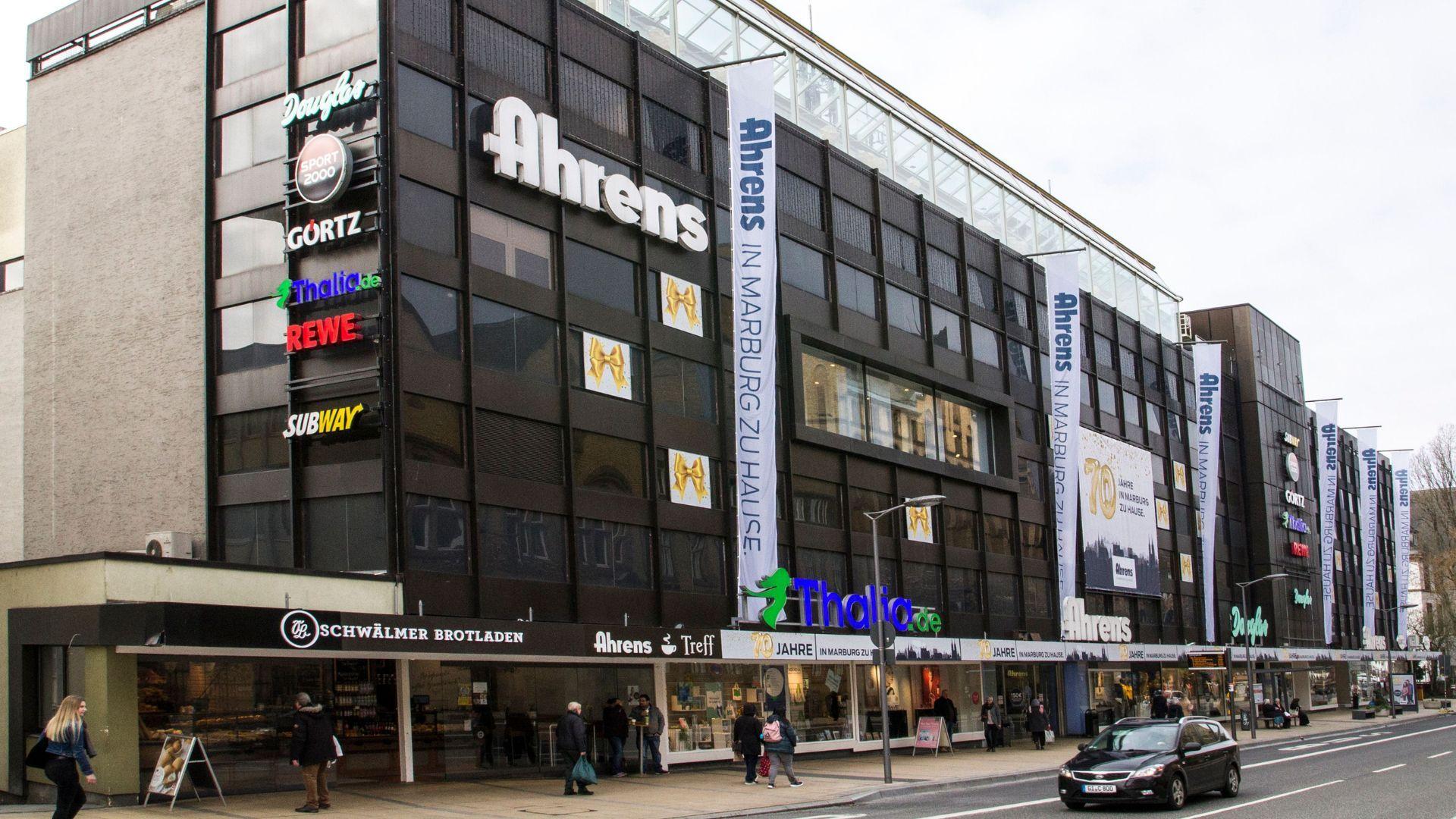 Large modern Ahrens department store building with multiple commercial signs on its dark facade.