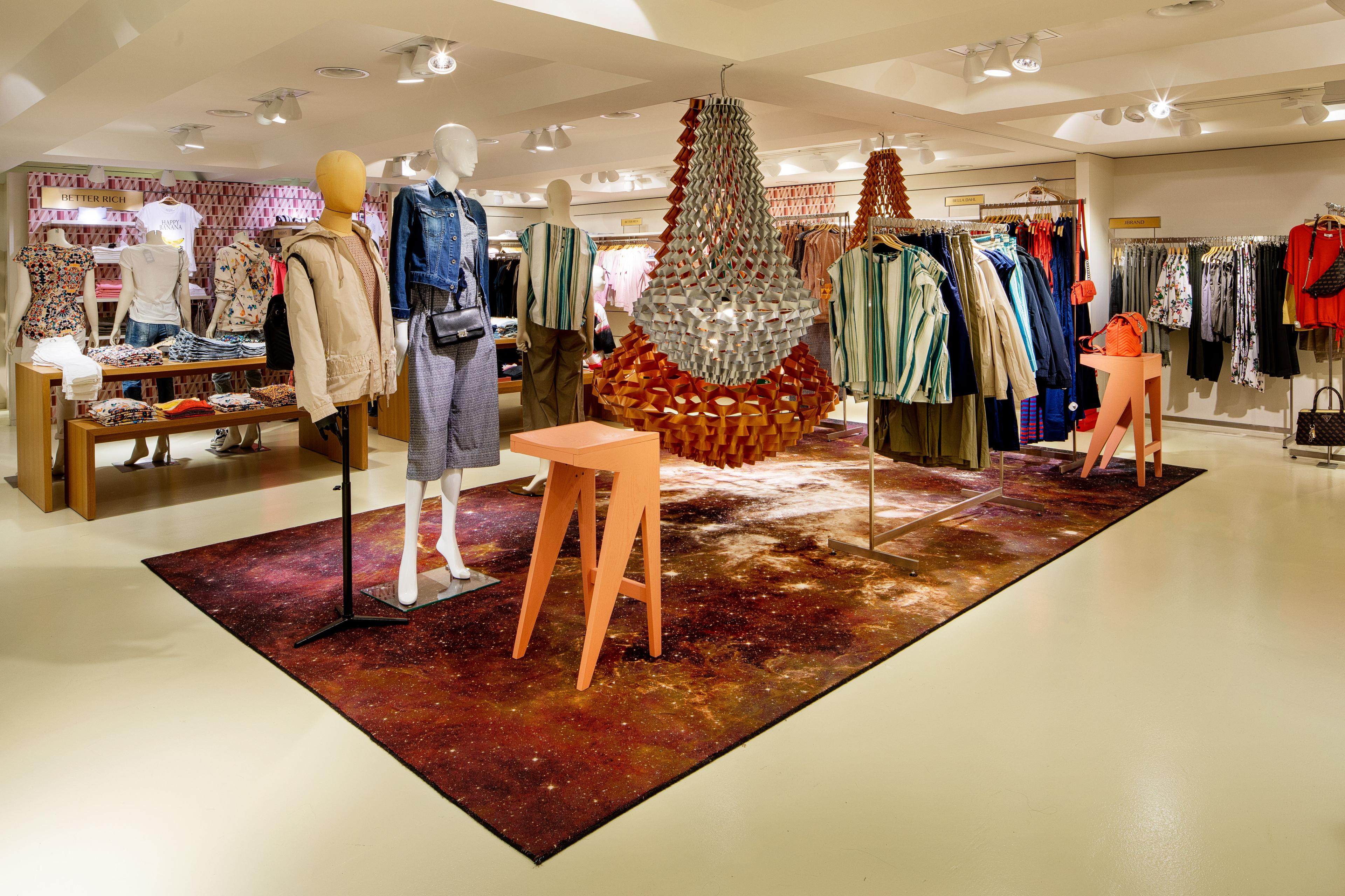Modern clothing boutique interior with mannequins, clothes racks, and a unique decorative light fixture.