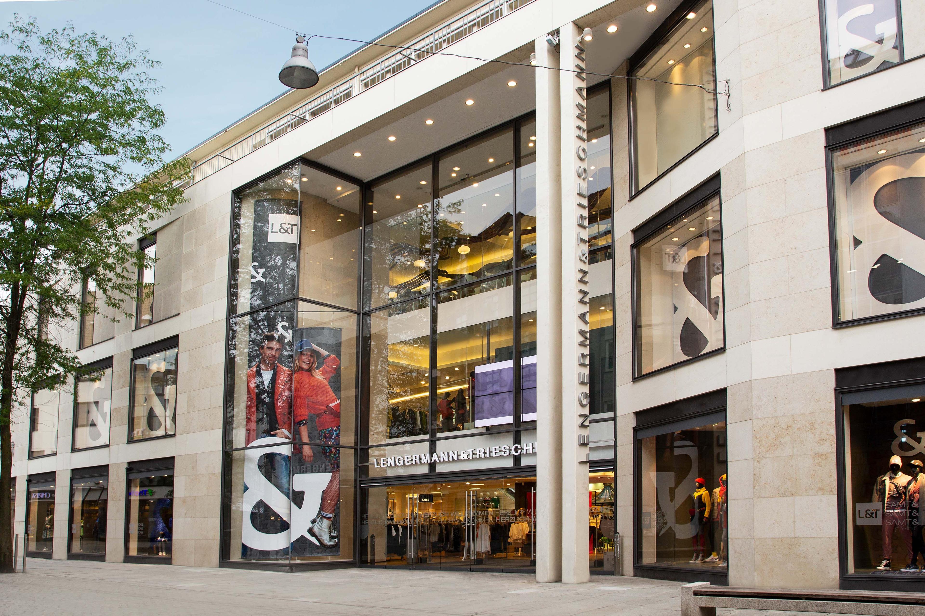 Modern stone building with large glass entrance and multiple retail window displays.