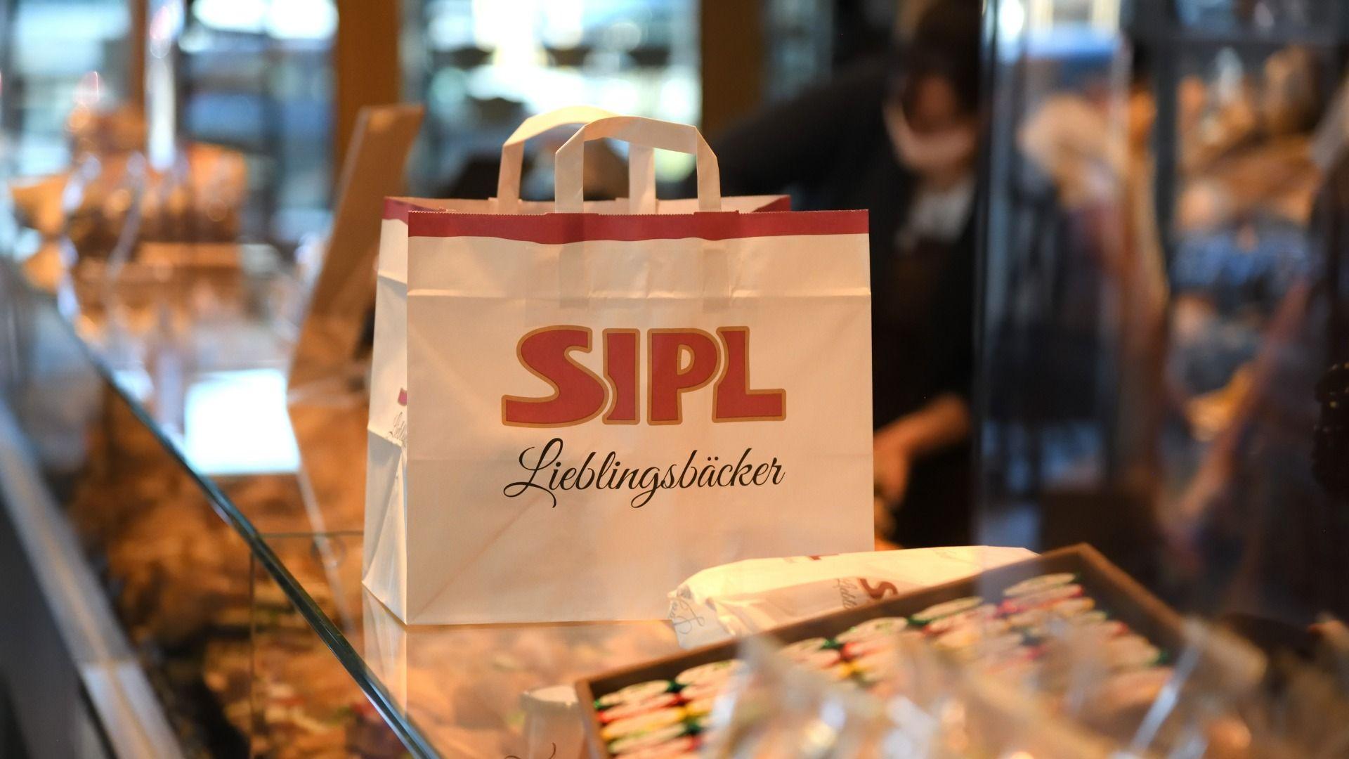 White paper bag with 'SIPL Lieblingsbäcker' logo on a bakery counter.