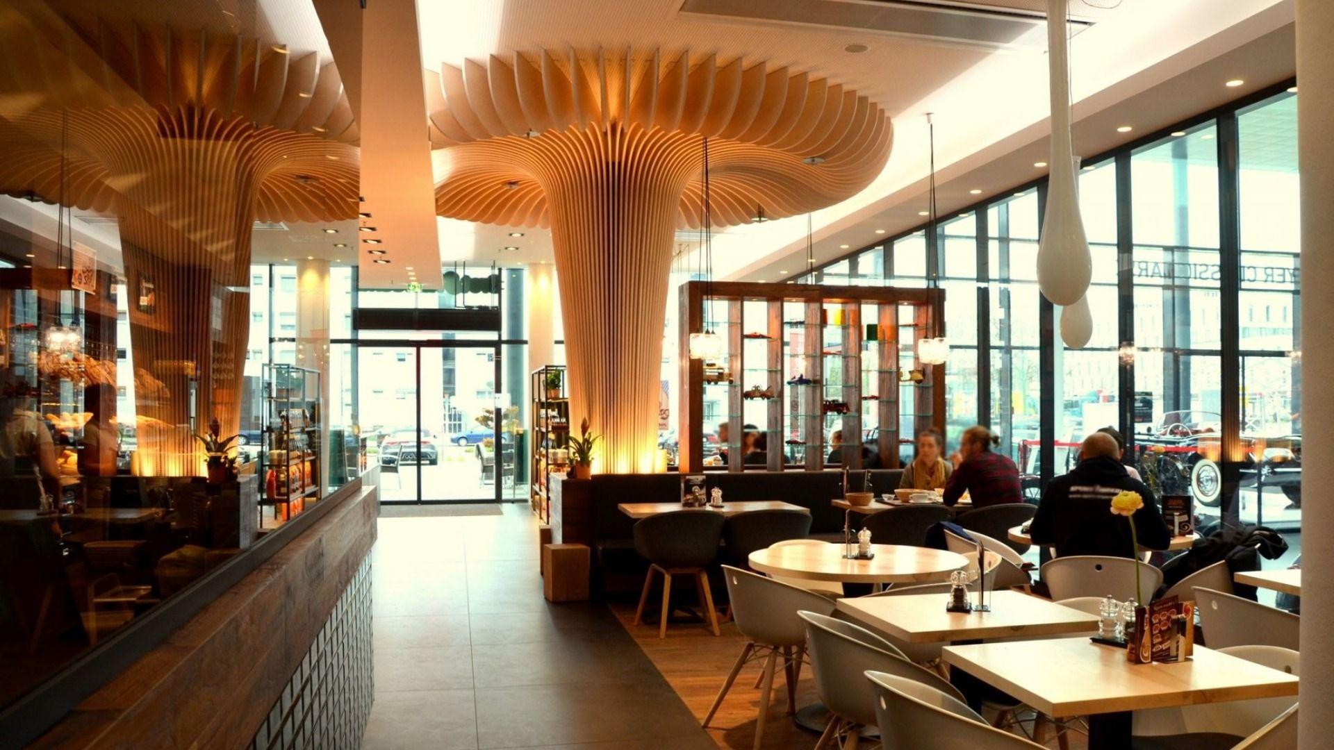 Modern cafe interior featuring a unique mushroom-shaped ceiling fixture, with tables and large windows.