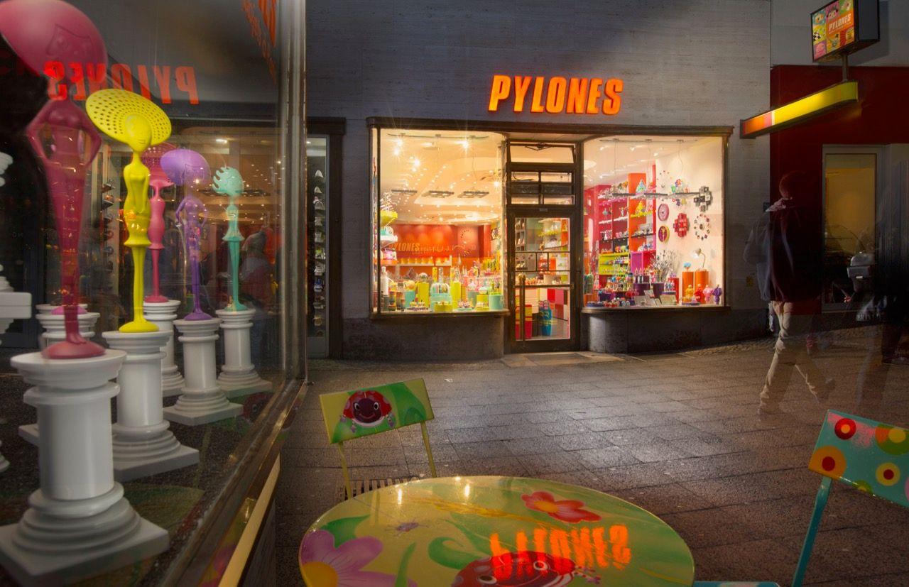 Pylones storefront at night displaying colorful, quirky merchandise and whimsical window reflections.